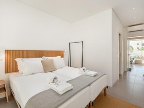 A modern hotel room with a large bed, wooden headboard, and a view of the outdoor area. - Luxury Villa, Sea View and Pool, Central Lagos (Lagos)