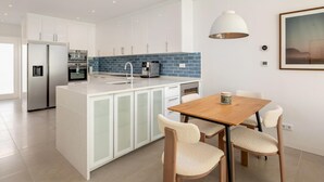 Una cocina moderna con armarios blancos, salpicadero azul y electrodomésticos de acero inoxidable.