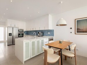 A modern kitchen with white cabinets, a blue backsplash, and stainless steel appliances. - Luxury Villa, Sea View and Pool, Central Lagos (Lagos)
