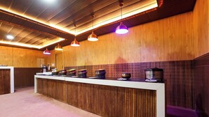 Un área de recepción con un mostrador de madera, varias máquinas de café e iluminación colgante.
