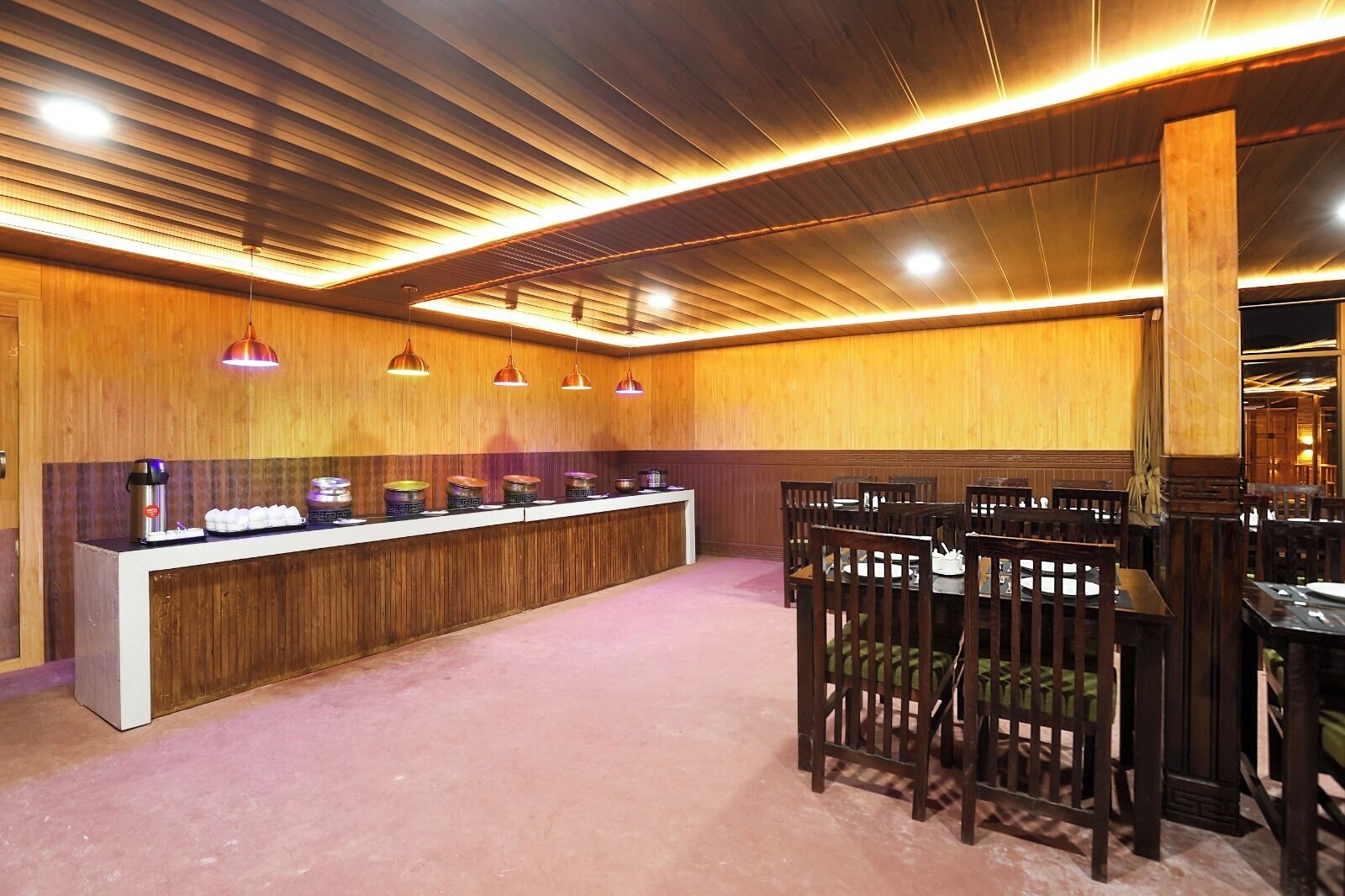Een restaurant met een lange toonbank, meerdere hangende lampen en houten lambrisering.