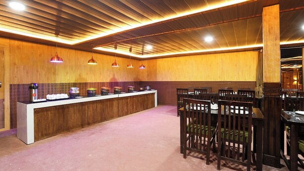 Un restaurante con una barra larga, varias luces colgantes y paneles de madera en las paredes.