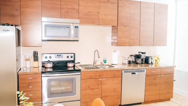 Cocina moderna con gabinetes de madera, electrodomésticos de acero inoxidable y salpicadero de azulejos.