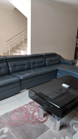 A modern living room with a sectional sofa, a glass coffee table, and a patterned rug.