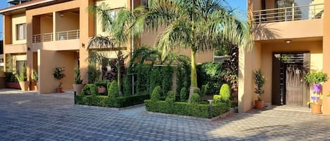 Edificio residencial con patio empedrado, plantas en macetas y un depósito de agua.