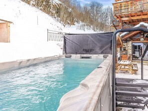 A hot tub with a wooden deck and a covered area, surrounded by snow and trees. - Chalet Villaroger by Interhome (Villaroger)