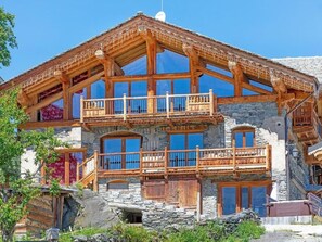 A multi-story wooden chalet with balconies, stone walls, and large windows. - Perle des Neiges by Interhome (Villaroger)
