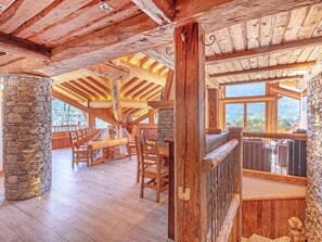 A spacious dining area with wooden tables and chairs, stone pillars, and a view of the outdoors. - Perle des Neiges by Interhome (Villaroger)