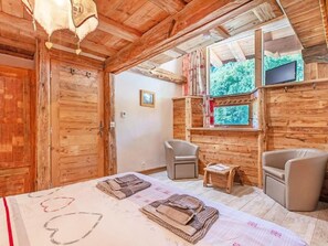 A wooden cabin interior with a bed, two chairs, a small table, and a window with a view of greenery. - Perle des Neiges by Interhome (Villaroger)