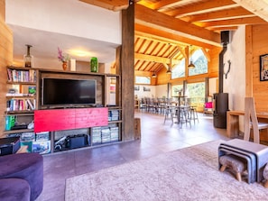 A spacious living area with a television, bookshelves, a fireplace, and a dining area with tables and chairs. - Chalet Cairn by Interhome (Peisey-Nancroix)