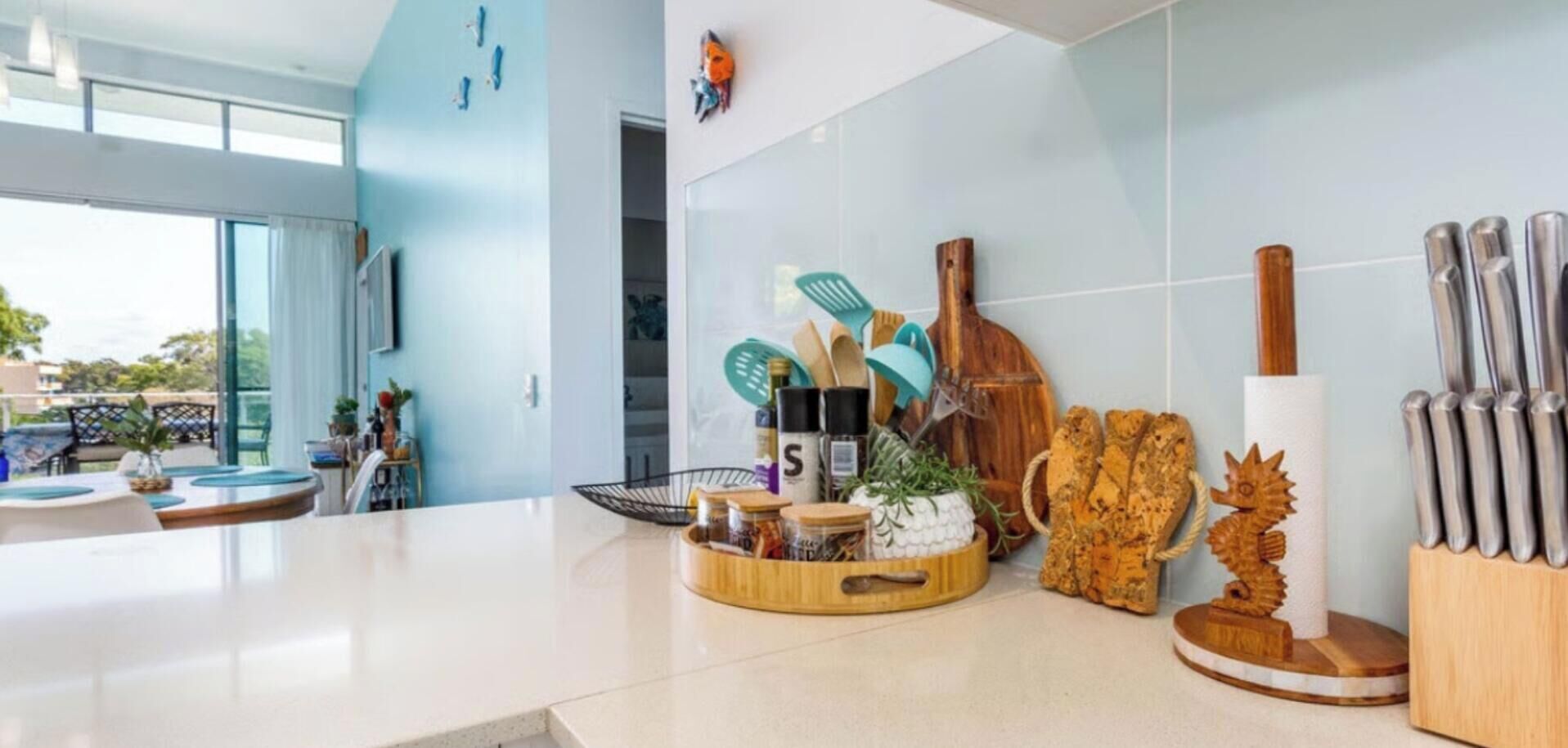 A modern kitchen with a large window, a wooden spice rack, and a knife block.