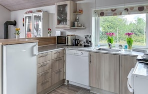 A kitchen with a refrigerator, microwave, coffee maker, and a window with a view of greenery. - Stunning home in Hemmet with WiFi (Hemmet)