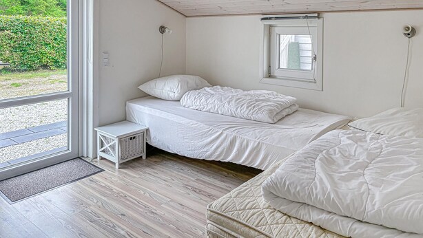 Un dormitorio con cama, una mesita de noche, una ventana y una puerta que da a un espacio exterior.