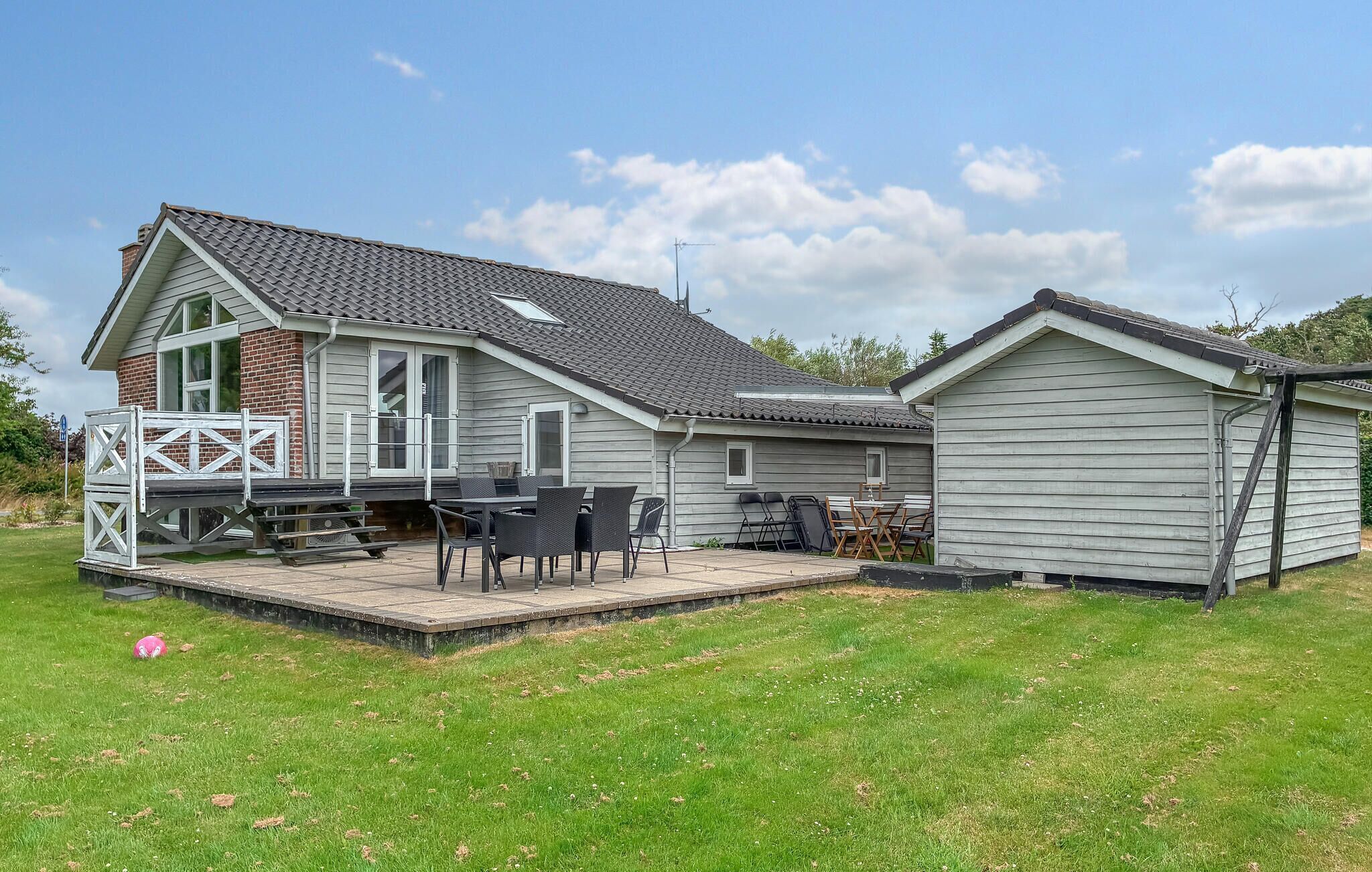 A residential property with a patio area, outdoor furniture, and a garage.