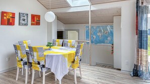 Comedor con una mesa dispuesta para cuatro, sillas de madera, un mapa del mundo en la pared y un tragaluz.