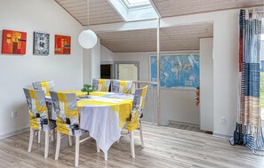 Ein Essbereich mit Tisch für vier Personen, Holzsesseln, einer Weltkarte an der Wand und einem Oberlicht.