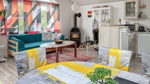 Una sala de estar con sofá, mesa de centro y chimenea. Hay una zona de cocina con armarios y microondas.