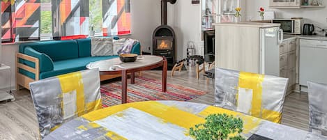 Un salon comprenant un canapé, une table basse et une cheminée. Il y a également un coin cuisine avec des placards et un four à micro-ondes.