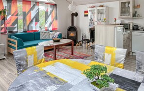 Ein Wohnzimmer mit einer Couch, einem Couchtisch und einem Kamin. Es gibt eine Küchenzeile mit Schränken und einer Mikrowelle.