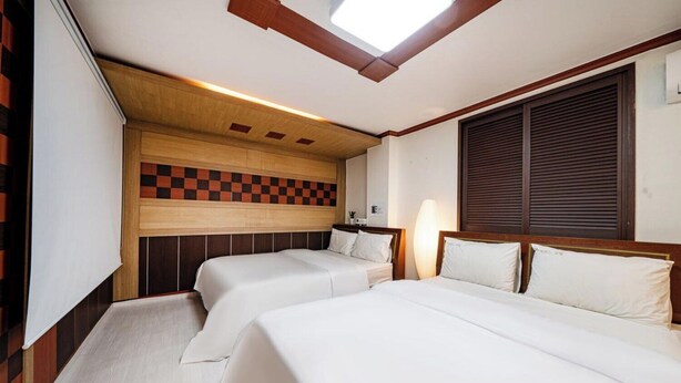 A hotel room with two beds, a skylight, and a checkered wall design.