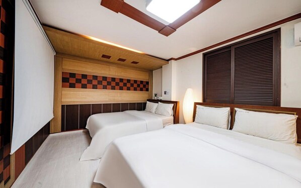 A hotel room with two beds, a skylight, and a checkered wall design.
