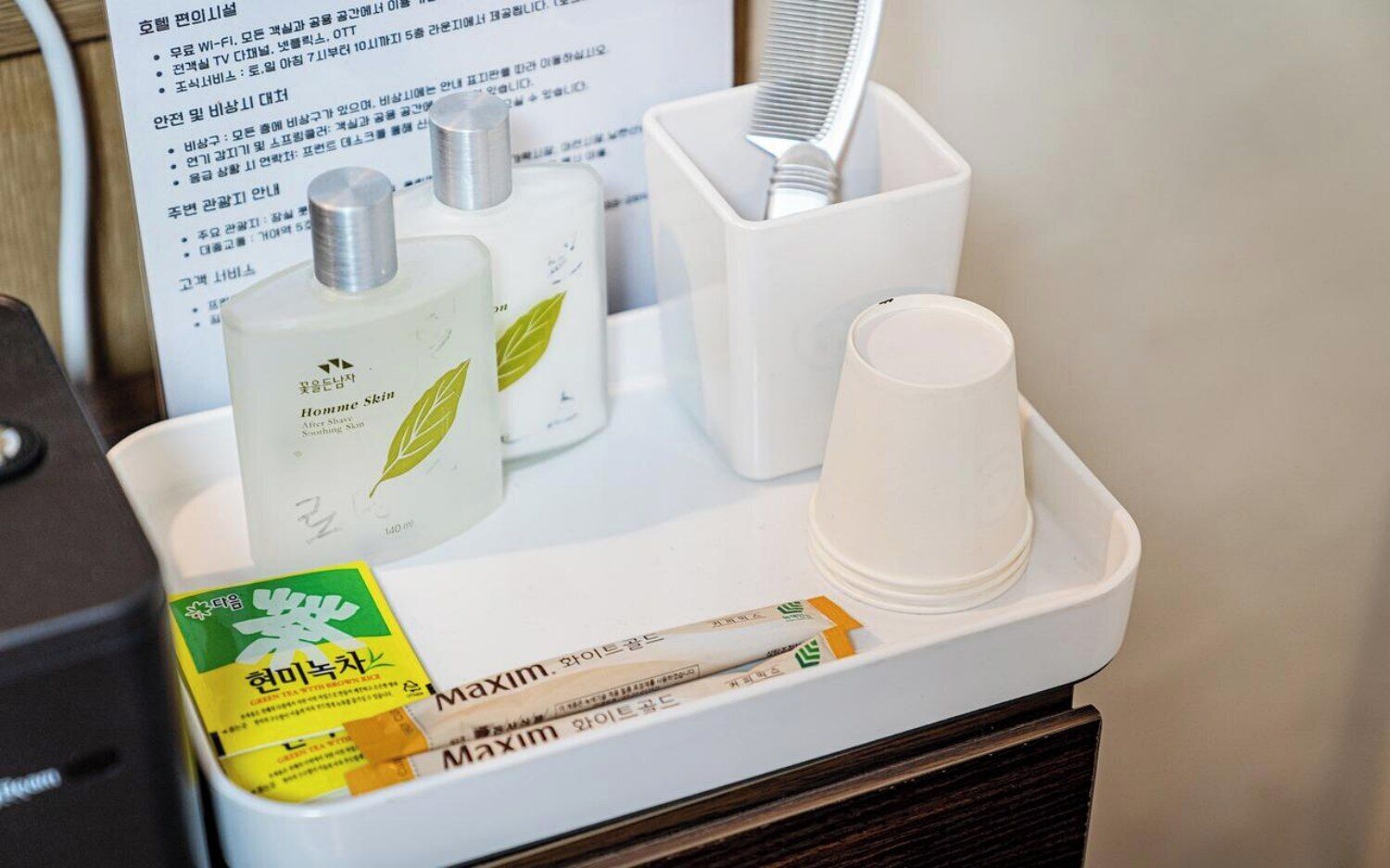 A hotel minibar with a bottle of 'Homme Skin After Shaving' and a box of 'Maxim' cigarettes.