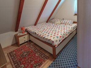A bedroom with a bed, a nightstand, a lamp, a window, and a patterned rug. - House Rukova Hiža by Interhome (Donja Stubica)