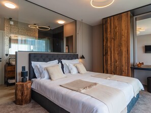 Ein modernes Schlafzimmer mit einem großen Bett, einer Wand im Holzoptik und einem Spiegel, der den Raum widerspiegelt.