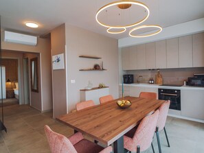 A modern kitchen with a wooden dining table, pink chairs, and a fruit bowl. - House Iris Croatica by Interhome (Oroslavje)