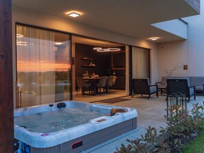 Eine moderne Außenpatio mit Whirlpool, Essbereich und Sitzgelegenheiten.