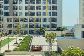 A modern residential building with multiple balconies, a swimming pool, and a well-maintained garden area. - UNA Apartments - Town Square Dubai (Dubai)