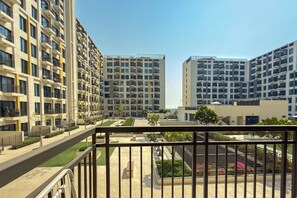 A modern residential building with multiple balconies, a well-maintained garden area, and a clear sky. - UNA Apartments - Town Square Dubai (Dubai)