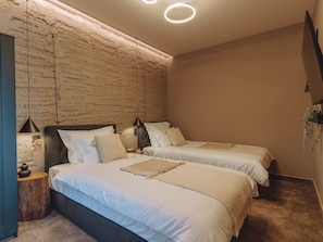 Ein Schlafzimmer mit zwei Betten, einer Steinwand und einer modernen Leuchte.