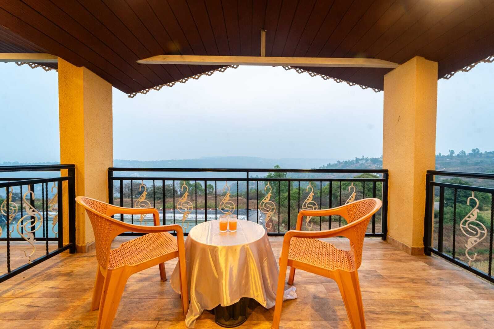 Ein Balkon mit zwei Korbstühlen und einem Tisch, mit Blick auf eine malerische Landschaft.