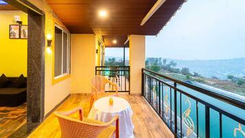 A balcony with a table and chairs, a view of a body of water, and a railing with decorative elements.