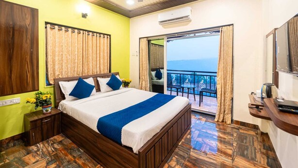 Ein Hotelzimmer mit Bett, Nachttisch, Schreibtisch und einem Balkon mit Blick.