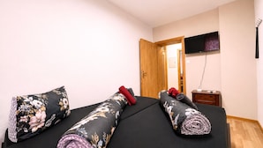 Una habitación con cama, almohadas, televisión y puerta de madera.