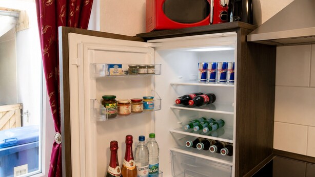 Un refrigerador lleno de diversos alimentos y bebidas, incluyendo vino y refrescos.
