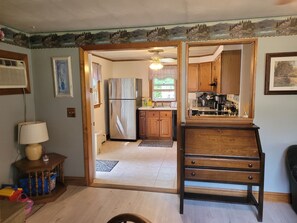 A kitchen with wooden cabinets, a stainless steel refrigerator, and a dining area with a wooden table and chairs.