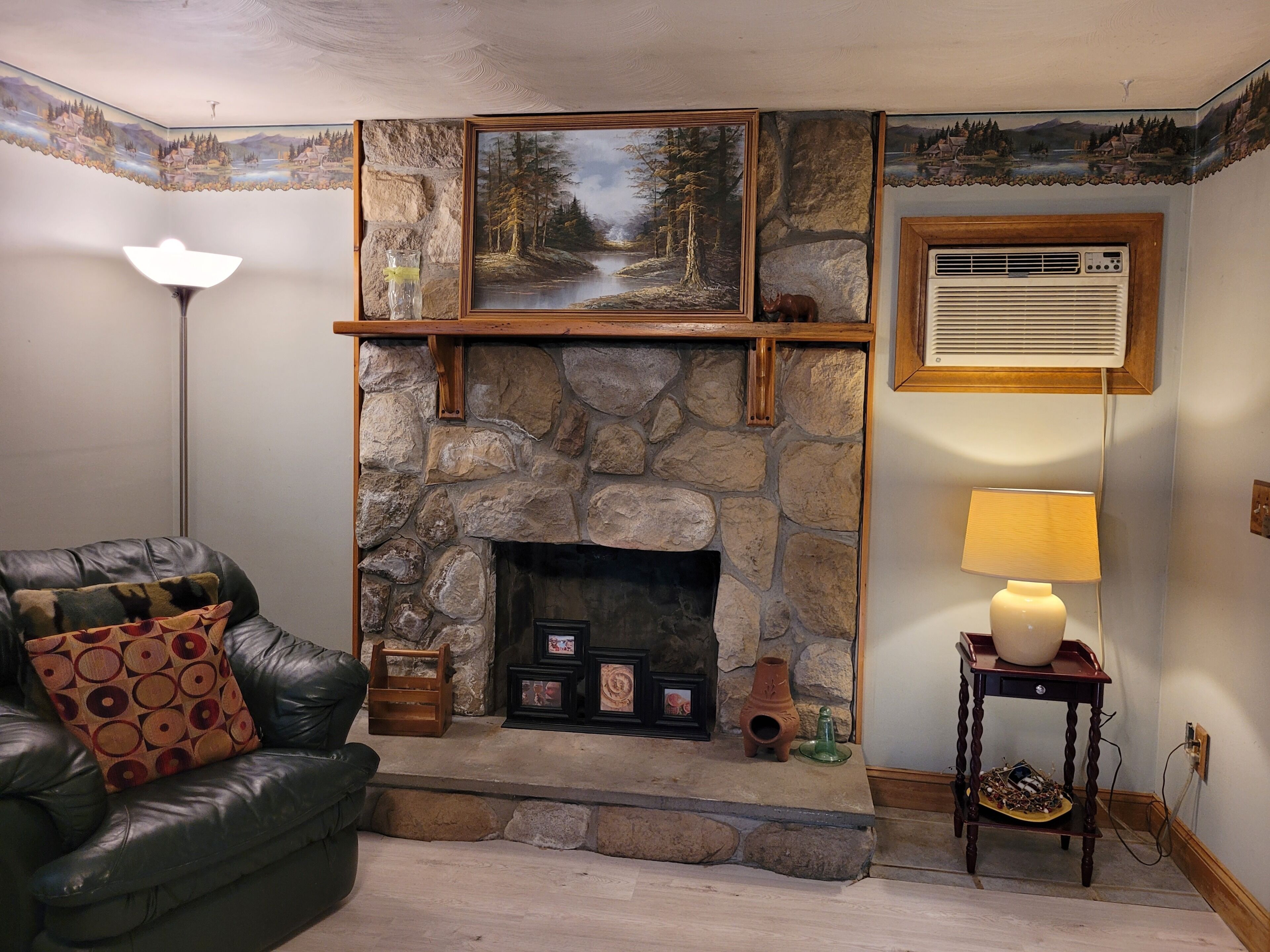 A living room with a stone fireplace, a leather sofa, a lamp, and a small table with decorative items.