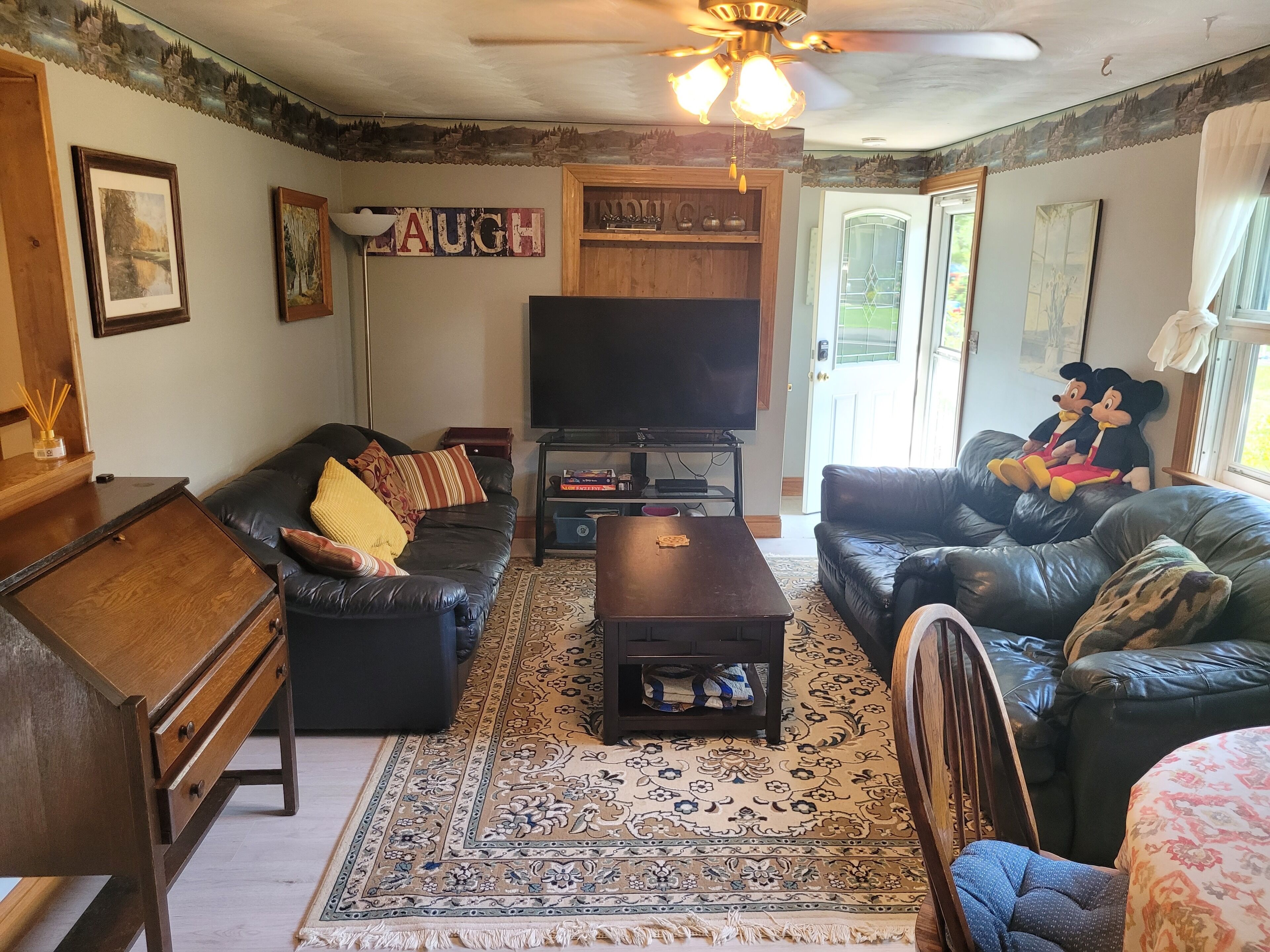 A living room with a sofa, a coffee table, a television, and a decorative rug.