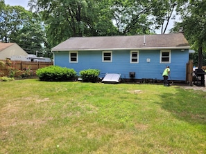 A residential house with a blue exterior, a fenced yard, and a person working near the house.