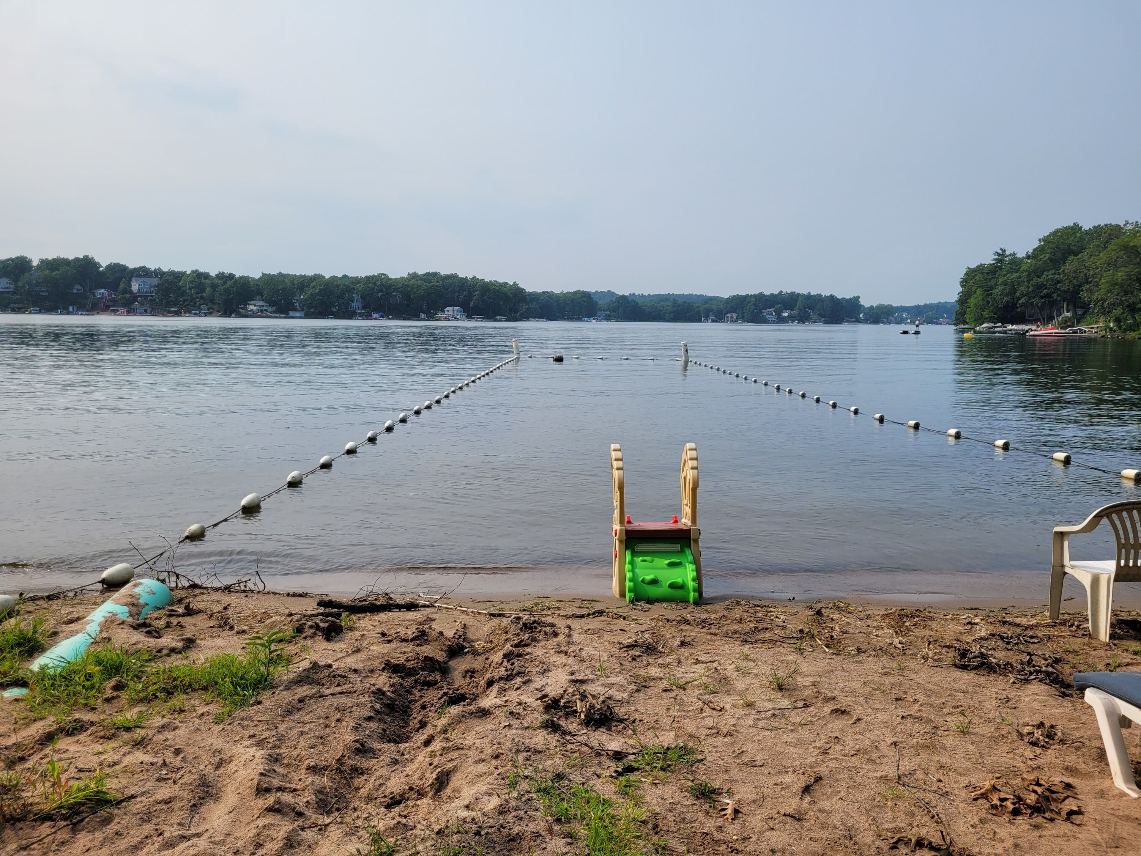 A sandy beach with a green lifeguard stand and a white lifebuoy.