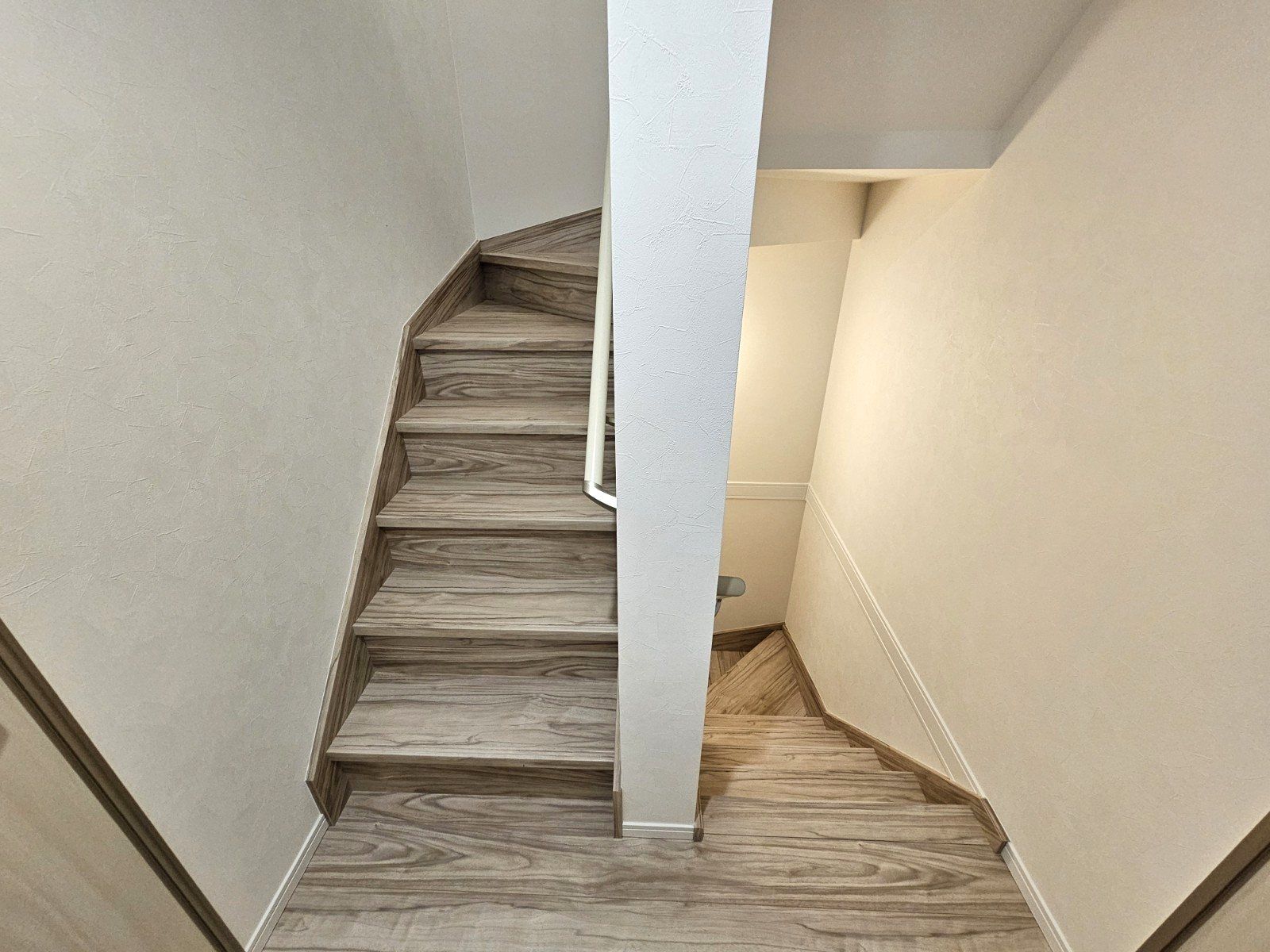 A spiral staircase with wooden steps and a white column in the center.