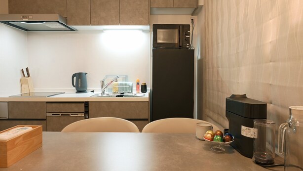 A modern kitchen with a microwave, refrigerator, and a coffee maker. - SA INN (Taito City)