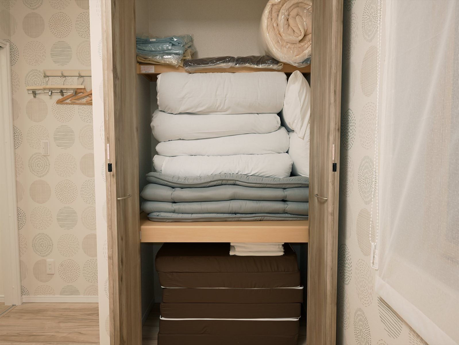 A closet with neatly stacked bedding and folded clothes.
