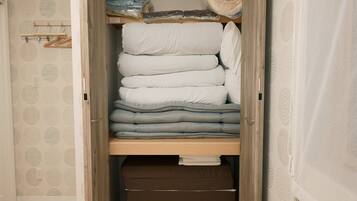 A closet with neatly stacked bedding and folded clothes.