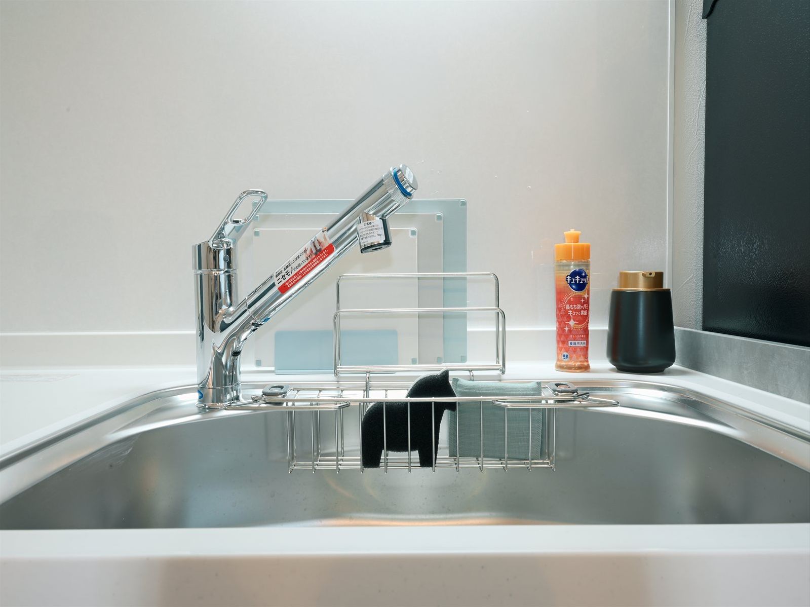 A modern kitchen sink with a chrome faucet, a soap dispenser, and a bottle of dish soap.