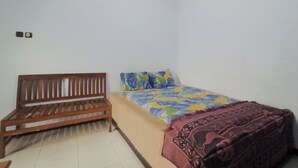 Una habitación pequeña con un banco de madera, una cama con colcha estampada y una manta decorativa.