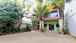 Un edificio de dos pisos con fachada verde y un patio empedrado.